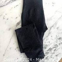 Folded pair of dark charcoal grey Lululemon pants laying on a marble surface showing fabric texture.