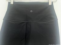 Front close-up of Lululemon logo on waistband and fabric detail of black compression pants