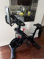 Side-angle view of complete bike showing frame, flywheel, tension knob, pedals and seat