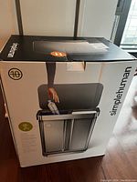 Photo of the original black and white Simplehuman box with image and branding visible, showing 10-year warranty and product image with dual compartments.