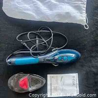 Photo showing the Tefal 2-in-1 handheld steamer/iron with power cord coiled alongside a heat-resistant cover with red pad on a black fabric background.