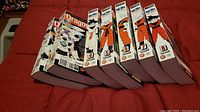 Seven Dragon Ball Z manga volumes arranged with the back covers and spines showing, numbered 2 through 8, placed on a red surface.