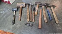 Wide view showing all hammers and mallets on concrete floor, arranged in a row