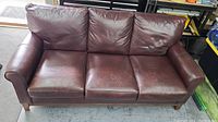 Full front view of three-seat leather sofa showing overall shape and wear