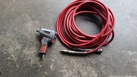 Full view of the IronForce impact wrench and red air hose coiled.