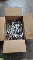 Top view of full box showing assorted combination wrenches and sockets in a cardboard box.