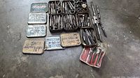 Wide layout of all tools including several tins with taps and dies, tap wrenches, die stocks, and a small bolt extractor kit.