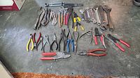 Top-down photo of all tools laid out: 10+ wrenches including adjustable and combination, multiple pliers of different types and sizes with colored handles