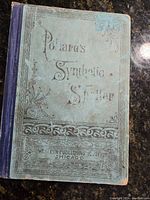 Front cover of Pollard's Synthetic Speller book, blue-green with faded decorative text and borders showing wear