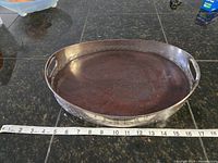 Overview of the oval tray showing wooden base and metal rim with handles and measuring tape for size reference.