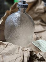 Textured glass float bottle with bulbous shape on crumpled paper background