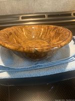 Photo showing side view of brown mottled splatterware oval bowl with rounded lip and visible age marks.