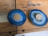 Two blue agate tea light holders with one tea light candle in each, photographed on a wooden surface.