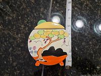 Top view of sugar bowl with lid showing hand-painted tree, footed base and measuring tape for scale.