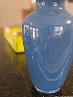 Close-up of large blue vase body showing glossy glaze and form.
