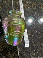 Side view showing the iridescent green glass with raised wave design and approximate 3 inch height.