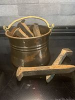 Copper pail filled with rusted railway ties, showing handle and patina on copper surface.