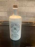 Front view of the vintage white ceramic bottle with printed label indicating Royal Charter Hudson's Bay 12 Year Old Rye Whisky, with wooden stopper on top.