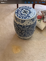Barrel-shaped ceramic stool with blue and white floral and ornate scroll designs on a light carpeted floor.