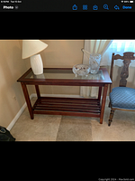Wood and glass hall table shown with glass top and lower wooden slatted shelf. Accessories on top not included.