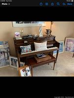 Upright piano with various decorative items on top and a matching wooden bench in front.