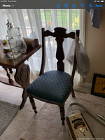 First image of a vintage wooden chair with blue patterned upholstery and carved backrest.