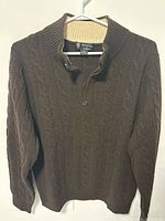 Full front view of brown cable knit Brooks Brothers Saxxon wool sweater with shawl collar and buttons.