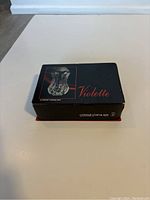 Photo of closed black box with image and brand labeling for Cristal D'arques Violette crystal glassware.