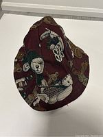 Side view of a maroon bucket hat with printed animal illustrations including an owl, a bear, and a rabbit.