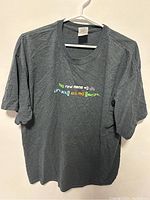 Full image of gray XL T-shirt hanging on a white hanger, showing the text on front.