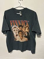 Front view of grey T-shirt with large printed graphic of Finnick from Hunger Games movies.