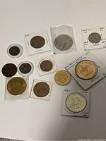 Overview of lot showing 11 coins, some in protective holders or sleeves with annotations