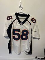 Front view of white Denver Broncos NFL jersey with number 58 and NFL logo on chest.