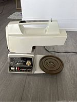 Front and side view of the vintage Oster Regency mixer base unit showing control panel, handle, and bowl base plate.
