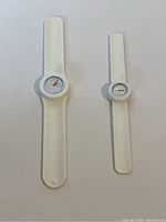 Pair of white slap watches with round faces and different sizes laid flat on white background