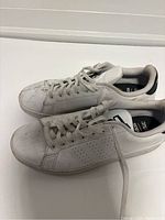 Pair of worn white Adidas sneakers showing overall view with dirt and creasing visible.