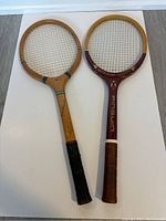 Two vintage wooden tennis rackets laid flat on white background showing full length and design