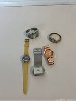Top view of 5 different watches laid out on white surface showing variety in bands and face styles.