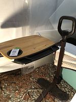 Side angle view of adjustable table showing wooden surface, black tray, and wheeled base.