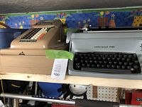 Antique adding machine and Underwood Five typewriter on a wooden shelf