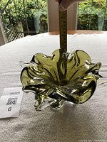 Side view of green and clear ruffled glass ornament, with a measuring tape showing height at about 3.5 inches