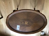 Top view of oval end table showing central inlay surrounded by wooden rim and removable glass top.