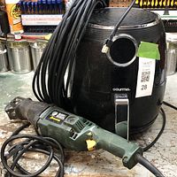 Photo showing a black Gourmia air fryer, a Greenlee reciprocating saw power tool, and a coiled black Ethernet cable on a workbench.