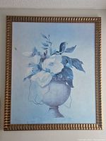 Front view of the large painting depicting blue-shaded flowers in a vase with a gold wooden frame.