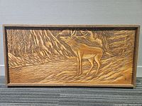 Full view of the rectangular wooden carving depicting a moose in a forest scene with frame.