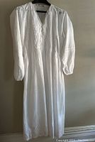 Full view of white cotton night dress on hanger showing full length, sleeve, and neckline design