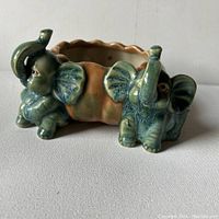 Front side view of the Majolica style elephant planter showing two green elephants and scalloped rim.