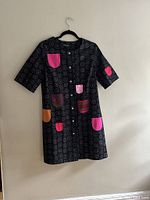 Front view of vintage Marimekko dress jacket with dark patterned fabric and multiple colorful patch pockets in pink, orange, and purple.