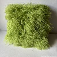 Front view of bright spring green Mongolian sheepskin pillow case showing long, curly fur texture.
