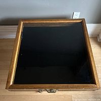Top view of the oak display box with closed glass lid showing the black velvet interior base.
